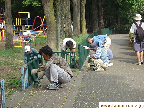 Workers repainting a fence on the path by the stream