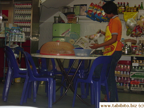 The waitress just finished putting a fly cover over some left-over dishes.  She's spreading the newspaper over other things too