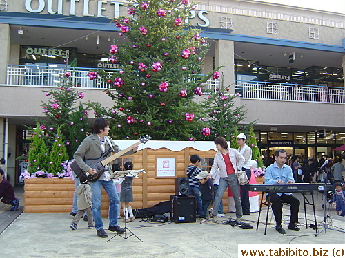 Musicians perform while parents chase after their kids who have wandered on stage