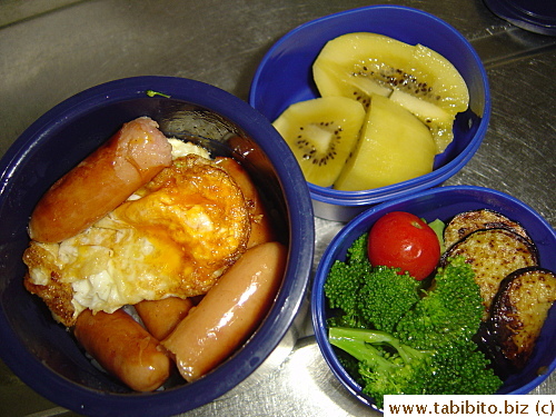 Sausages and fried egg, sauteed broccoli, grilled eggplant, cherry tomato, kiwi fruit